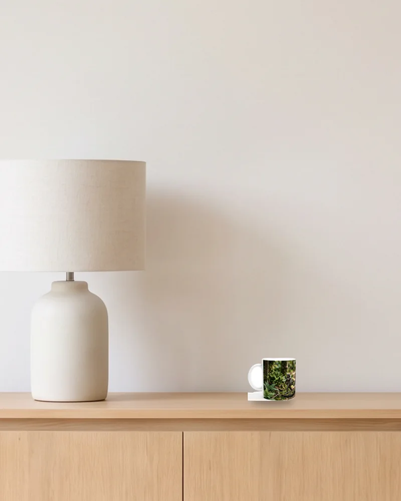 Mug, 11 oz (about 3.7 in tall), on an oak sideboard beside a table lamp, shown to scale with example artwork